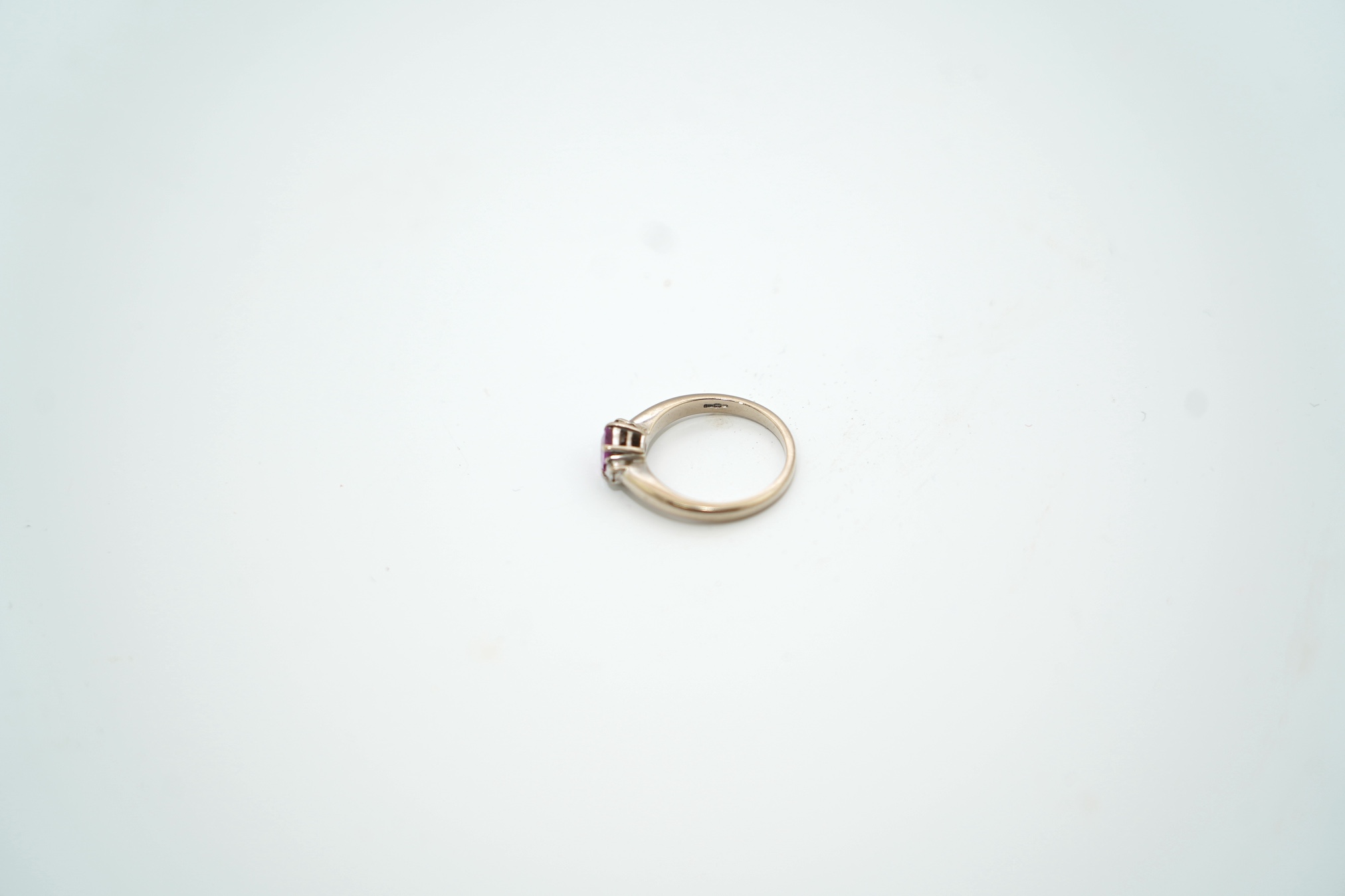 A modern 18ct white gold, single stone pink sapphire and two stone diamond set ring, size J, gross weight 3.7 gram. Condition - good